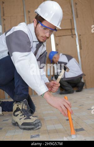 constructon worker removing old floor tiles Stock Photo