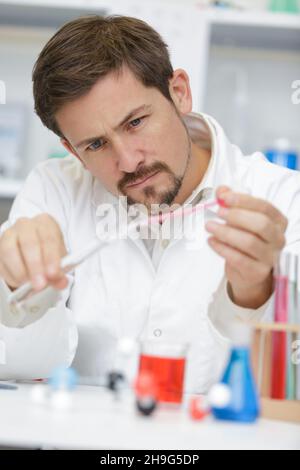 young man scientist using auto-pipette with flasks Stock Photo