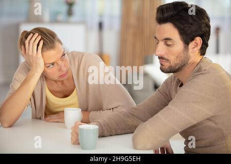 unhappy couple quarrelling sitting apart indoors Stock Photo