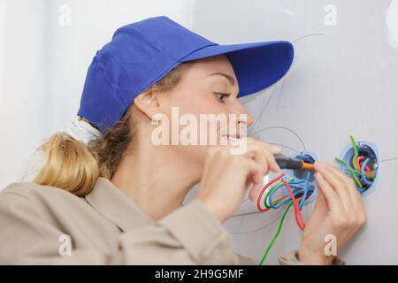 female electrician fixing electric cables in socket Stock Photo