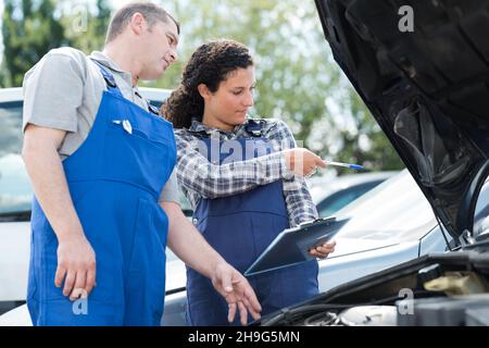 two workers looking at car documents outdoors Stock Photo