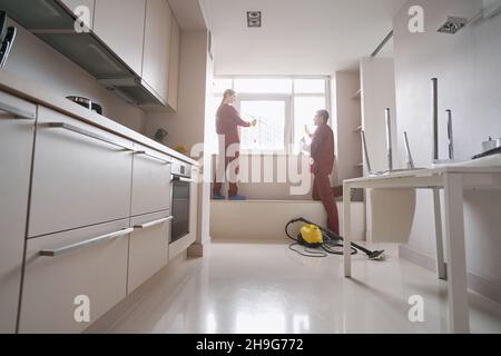 Two cleaners in rubber gloves washing windowpane Stock Photo