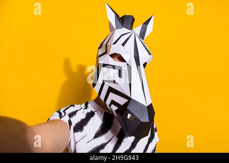 Portrait of bizarre surreal guy in zebra mask make selfie video call theme festival isolated over yellow color background Stock Photo
