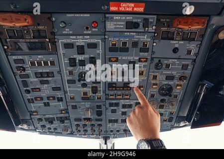 Finger of aircraft pilot turning on windshield heating Stock Photo