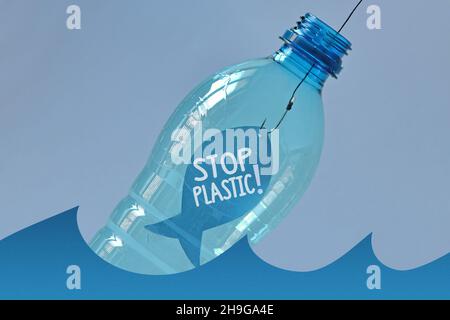 Fish on a hook with the written Stop plastic! in a plastic bottle floating on water - Concept of ecology and stop plastic pollution Stock Photo