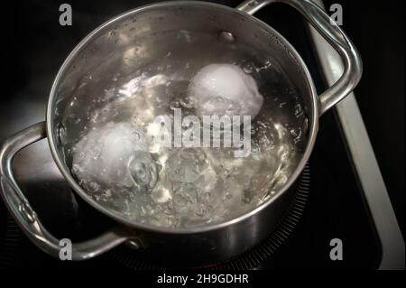 Two white eggs are boiled in a saucepan. Stock Photo