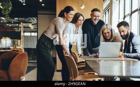 Group of diverse businesspeople using a laptop while collaborating on a new project. Team of happy businesspeople looking at the laptop screen while w Stock Photo