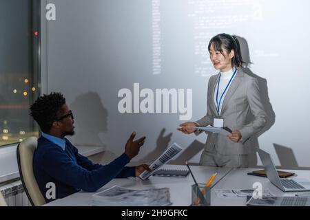 Two contemporary programmers with papers discussing new information and working points at meeting Stock Photo
