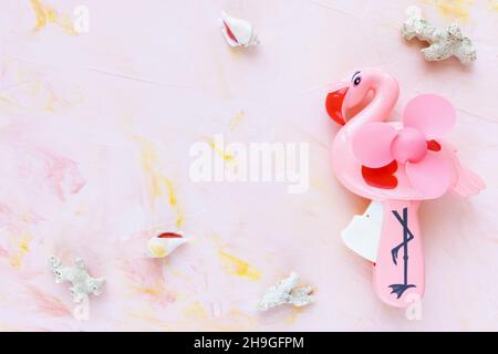 Abstract summer background with seashells and hand flamingo fan on pink. Lifestyle, planning sea vacation, summer holidays concept. Flat lay, top view, copy space Stock Photo