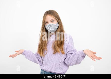 pretty blonde girl in purple wool sweater with nose mouth mask is standing in front of white background Stock Photo