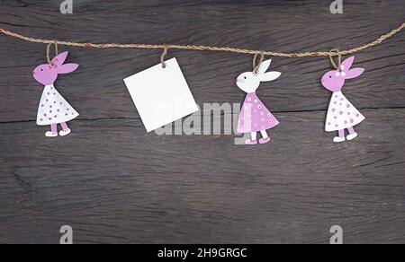 Easter garland on a wooden background. Bunnies with paper for copy space Stock Photo