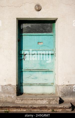 Ugly building with a turquoise color iron door. Aqua blue metal door. Stock Photo