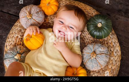 happy cute baby on the basket with different small baby pumpkins Stock Photo