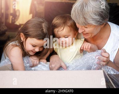 children and grandmother open the box. woman and granddaughters look into the parcel Stock Photo