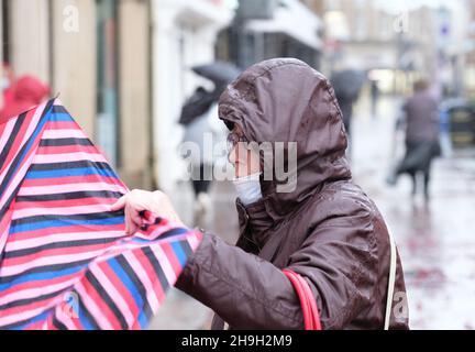 Hereford, Herefordshire, UK - Tuesday 7th December 2021 - UK Weather - A shopper struggles to hold on to her umbrella in Hereford city centre during strong winds and heavy rain as Storm Barra aprroaches from the West - Photo Steven May / Alamy Live News Stock Photo