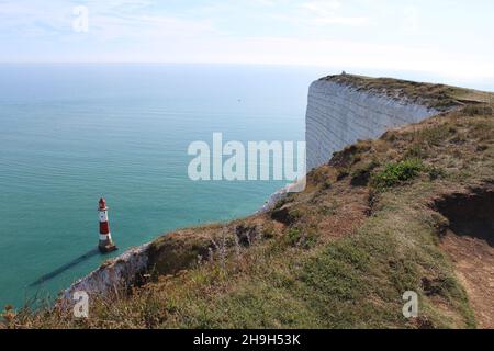 Seven Sisters Cliffs. View of the Beachy Head Lighthouse casting a shadow beneath the white cliffs, clear blue Atlantic ocean and summer sky (Sussex) Stock Photo