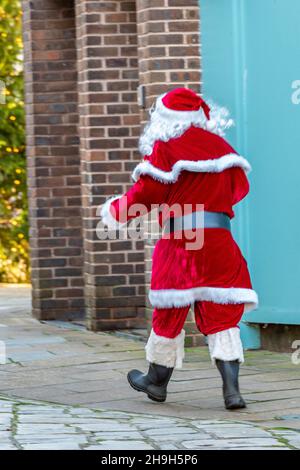 man dressed in santa claus or father christmas costume, santa walking through town, father christmas outfit worn by man walking through city centre. Stock Photo