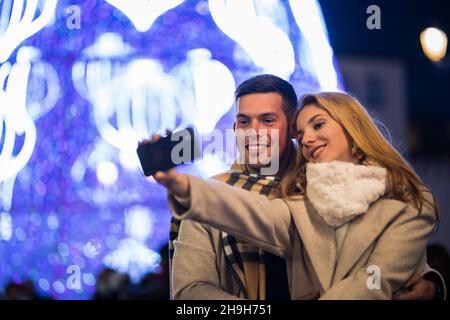 Young couple taking a selfie on the street at christmas Stock Photo