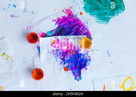 Blots and spots of bright watercolors on white paper. Top view on jars and mixed colors paints. Bright background for artists and designers Stock Photo