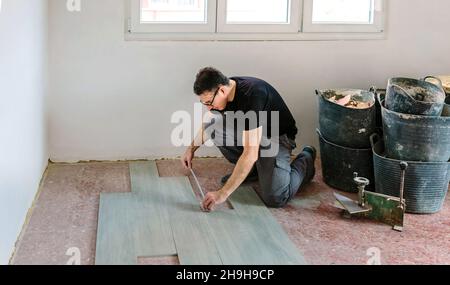 Bricklayer measuring tiles to install a floor Stock Photo