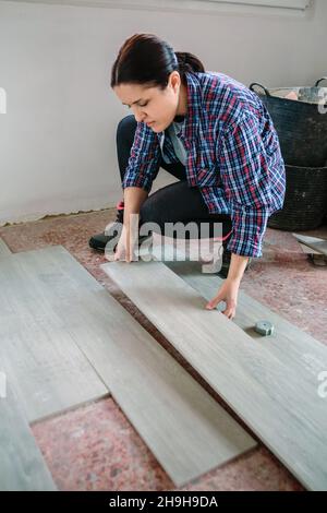 Female bricklayer placing tiles to install a floor Stock Photo