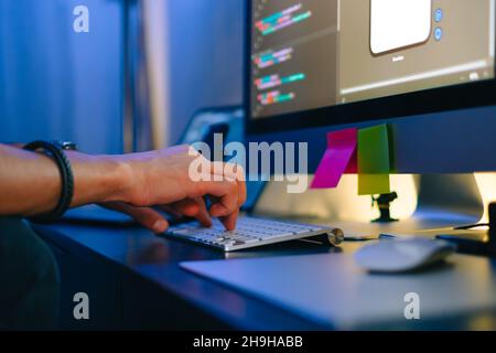 Mobile developer writes program code on a computer, typing on keyboard, programmer work in home office. Stock Photo