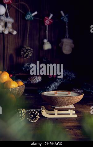 One handmade candle in a coconut shell on the background of a Christmas decor. Stock Photo