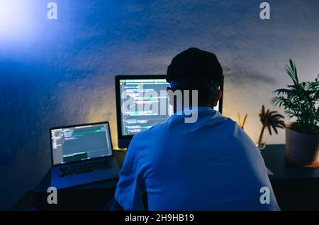 Young man mobile developer writes program code on a computer, programmer work in home office. Stock Photo
