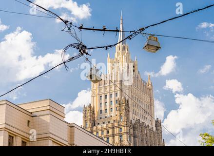 Old hanging streetlamps on cables or wires suspended above the road. One of Moscow Stalinist highrises in background. Russia Stock Photo
