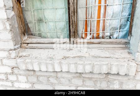 Lower part of wooden window frame curtained with dirty material in a brick wall Stock Photo