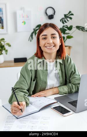Woman remotely working at home with laptop computer. Young businesswoman planning her time. Concept of online business, freelance, home office and tel Stock Photo