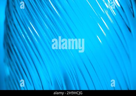 Ribbed glass with wavy pattern illuminated in blue light. Creating volume with light. Abstract background with copy space. Stock Photo