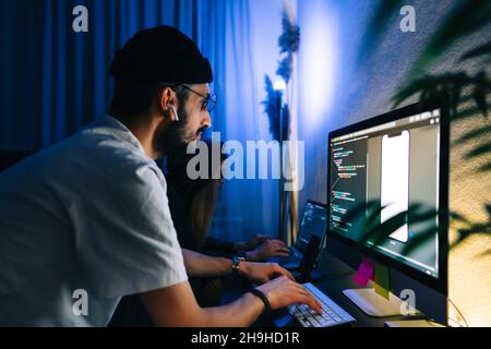 Mobile developers team writes program code on a computer, programmers work in home office. Stock Photo