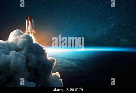 Space rocket lift off into cosmos with smoke and blast on a background of the blue planet earth. Spacecraft flies in space with a starry sky near the Stock Photo