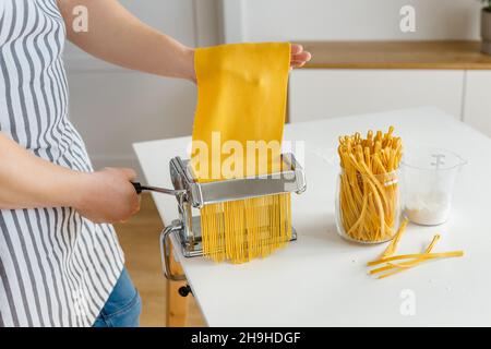 Man in apron making spaghetti with noodle cutter. Close-up pasta