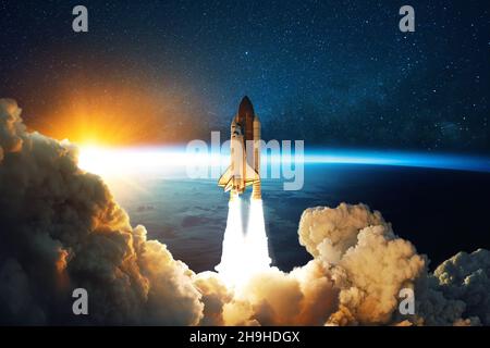 Rocket lift off. Space shuttle with smoke and blast takes off into space on a background of blue planet earth with amazing sunset. Successful start of Stock Photo