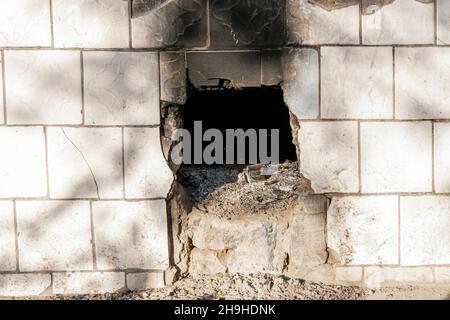 Blackened roughly made vent hole in brick cement damaged wall Stock Photo
