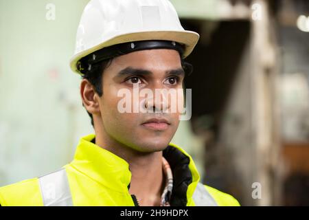 Profile view of young technician in checked shirt inspecting industrial machine Stock Photo