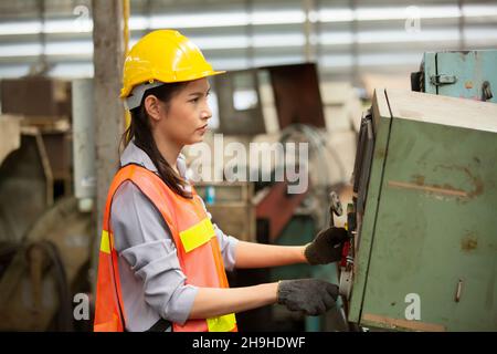 Profile view of young technician in checked shirt inspecting industrial machine Stock Photo
