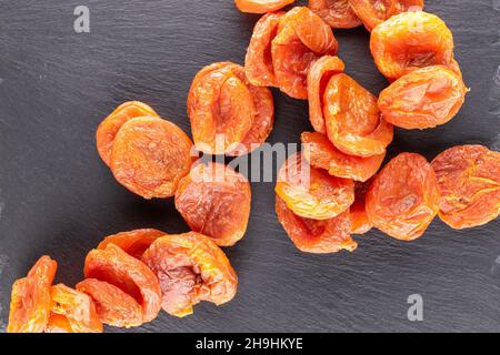 Several sweet dry apricots, close-up on a slate stone, top view. Stock Photo