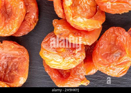 Several sweet dry apricots, close-up on a slate stone, top view. Stock Photo