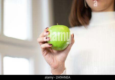 green apple standing in woman's hand, on isolated background Stock Photo