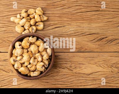 Canjica, hominy or white corn popcorn, sweet popcorn in a bowl over wooden table with copy space. Stock Photo