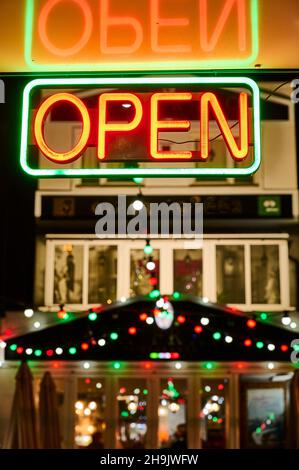 Neon open sign in front of restaurant at night reflected in ceiling Stock Photo