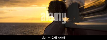 Silhouette of a woman enjoying and adminring a colorful sunset against a vintage van car. Concept of people and travel summer activity Stock Photo