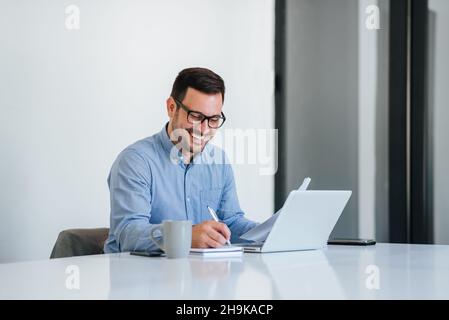 Portrait of a cheerful man having video call on laptop computer cheerful businessman using laptop in bright office space young smiling entrepreneur wo Stock Photo