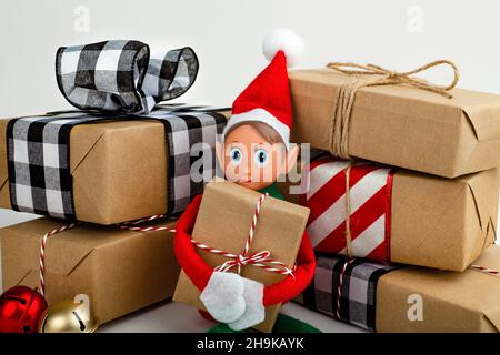 Close up of a Christmas Elf sitting in a stack of gift boxes  Christmas spirit, Christmas family tradition. Stock Photo