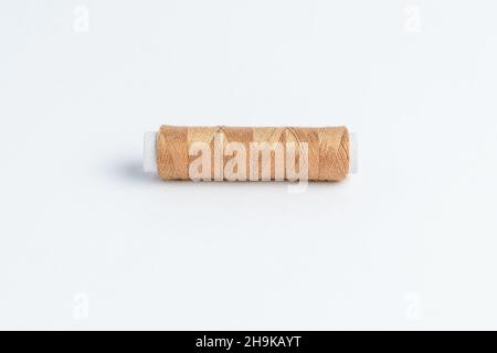 One vivid brown cotton spool of thread isolated on a white table Stock Photo