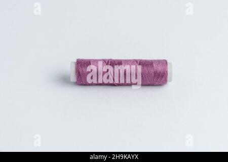 One vivid purple cotton spool of thread isolated on a white table Stock Photo