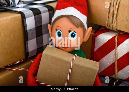 Close up of a Christmas Elf sitting in a stack of gift boxes  Christmas spirit, Christmas family tradition. Stock Photo
